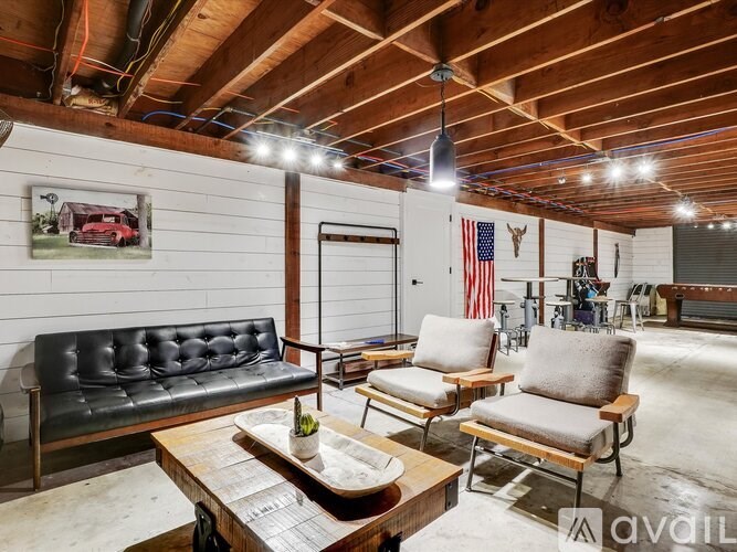 A living room with a black leather couch, two wooden chairs, and a coffee table.