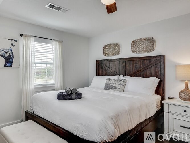A bedroom with a large bed, a window with curtains, and a ceiling fan.