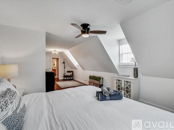 A bedroom with a bed, a ceiling fan, and a window.