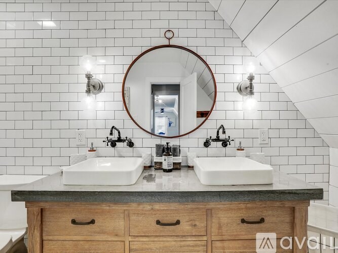 A bathroom with a round mirror and two sinks.