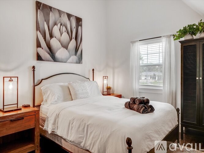 A bedroom with a large bed, a wooden headboard, and a painting of a flower above the bed.