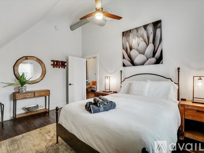 A bedroom with a large bed, a ceiling fan, and a painting of a flower on the wall.