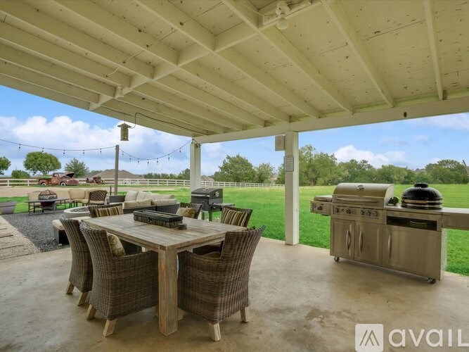 A covered patio with a table and chairs and a grill.