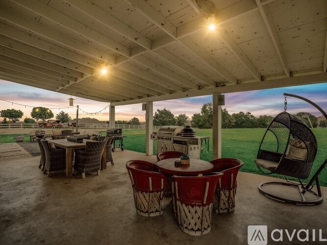 A covered patio area with a table set for four and a hanging chair.