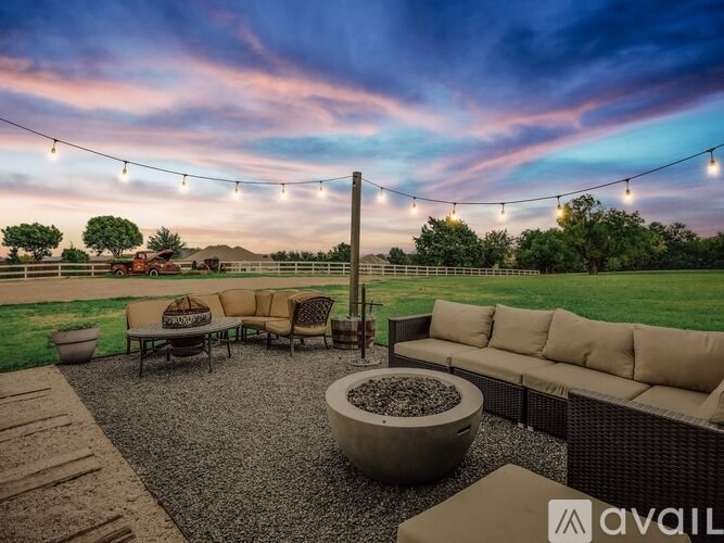 A patio with a couch, chairs, and a table with a bowl of rocks in the center.