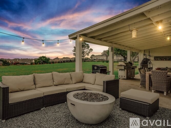 A patio with a couch, table, and chairs under a string of lights.