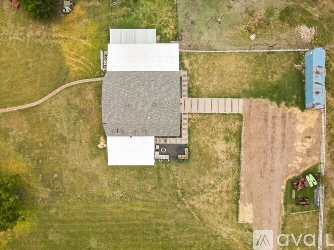 A house with a grey roof is surrounded by a grassy area.