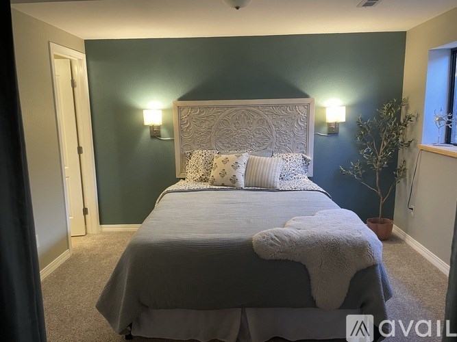A bedroom with a bed in the center and a wall sconce on the wall.