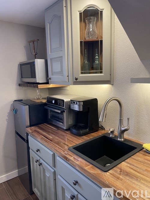 A kitchen with a sink, a refrigerator, a microwave, and a coffee maker.
