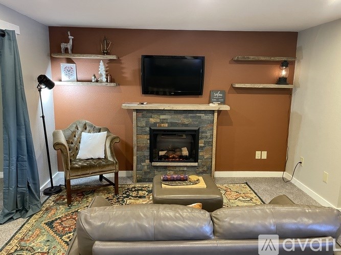 A living room with a fireplace and a television mounted above it.