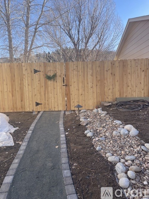 A wooden fence with a gate and a small garden in front.