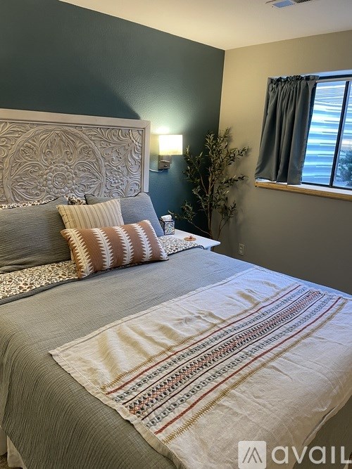 A bedroom with a bed, pillows, and a decorative headboard.