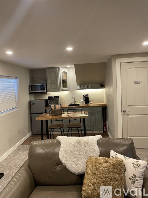 A living room with a brown couch and a kitchen area in the background.