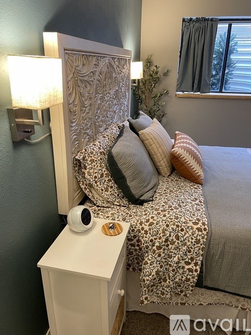 A leopard print bed with a white nightstand and a lamp on the wall.