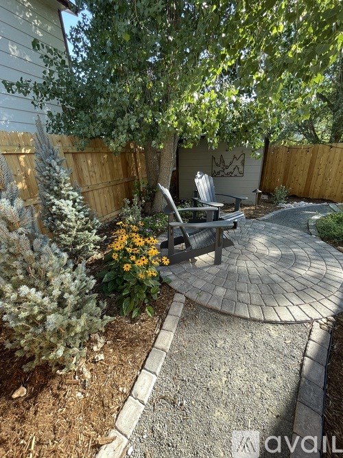 A backyard with a circular patio and a bench.