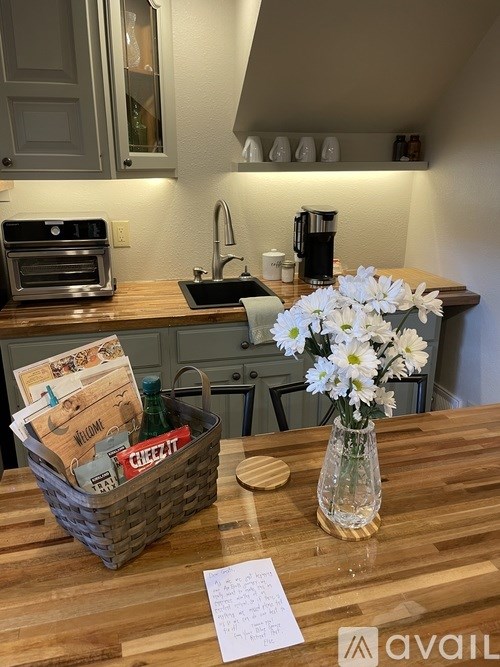 A kitchen with a wooden table, a basket with cards and a vase with white flowers.