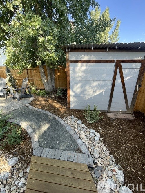 A backyard with a wooden deck and a stone pathway.