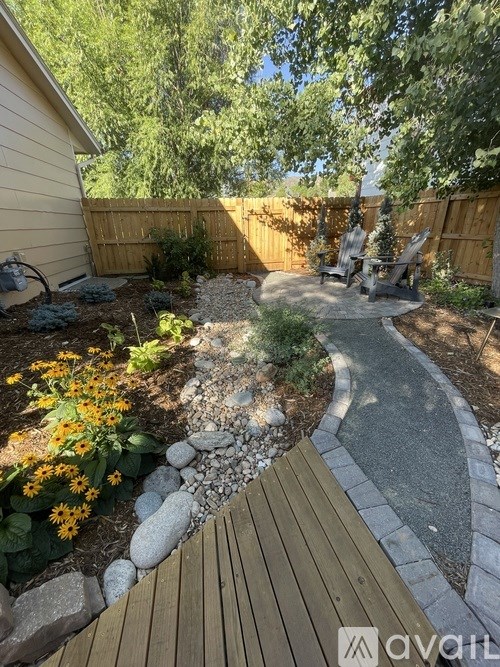 A backyard with a wooden deck and a gravel path.