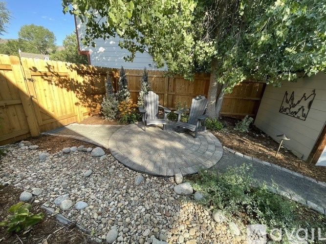 A backyard with a gravel patio and a wooden fence.