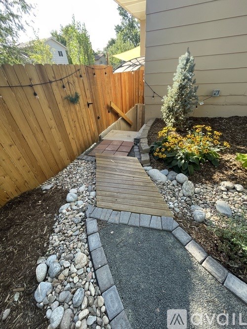A wooden fence and a stone pathway lead to a wooden gate.
