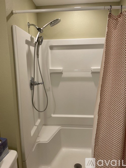 A white shower stall with a shower head and a curtain.