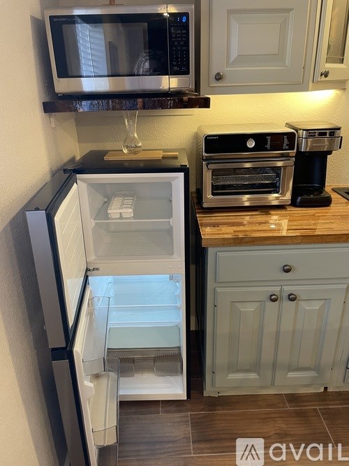 A kitchen with a black fridge and a black microwave above it.