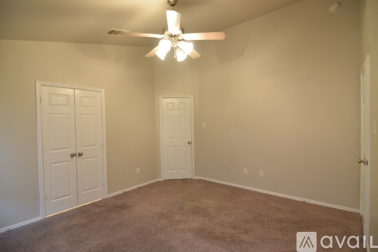 A room with a carpeted floor, a door, and a window with blinds.