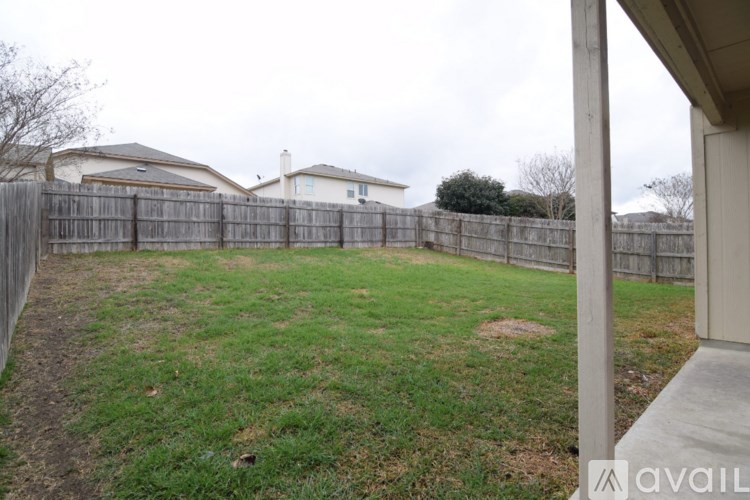 A backyard with a wooden fence and a grassy area.