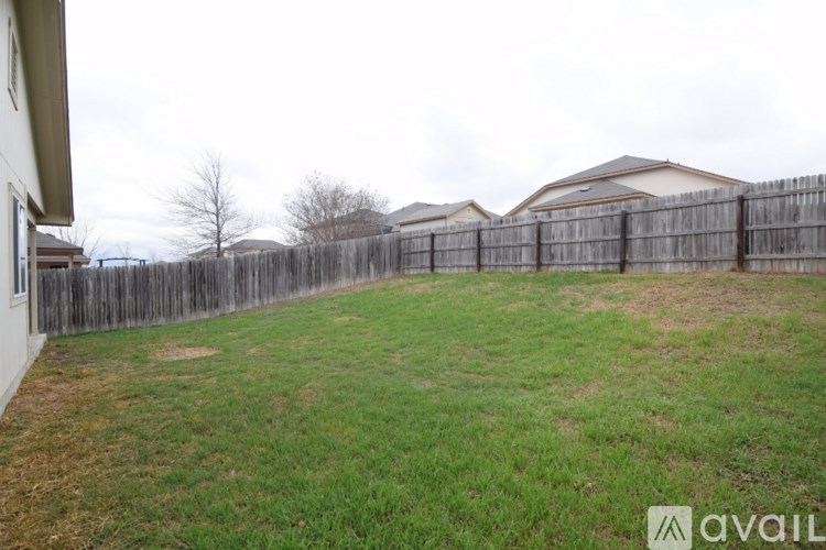 A backyard with a wooden fence and a grassy area.