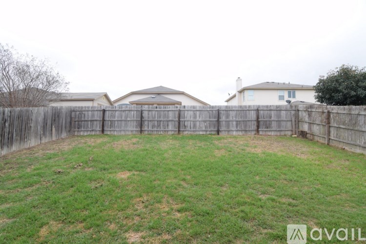 A backyard with a wooden fence and a house in the background.