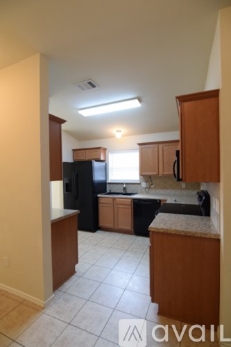 A kitchen with wooden cabinets and a black refrigerator.