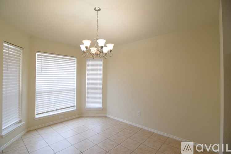 A room with a chandelier, two windows with blinds, and a tiled floor.