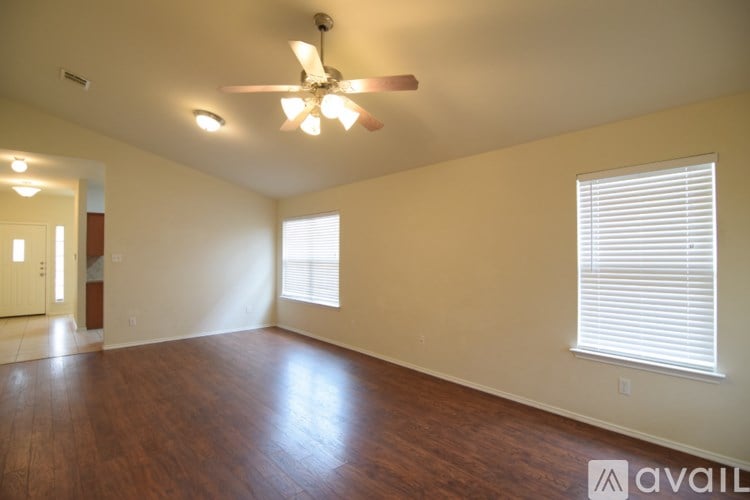 A room with a ceiling fan and wooden flooring.
