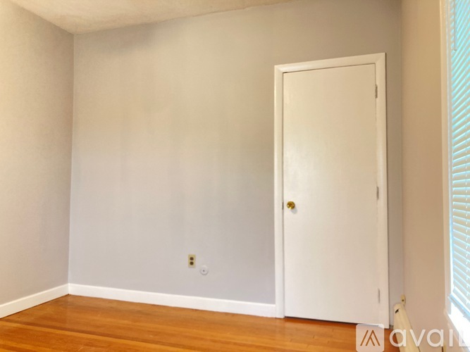 A white door is in a room with wooden floors and white walls.