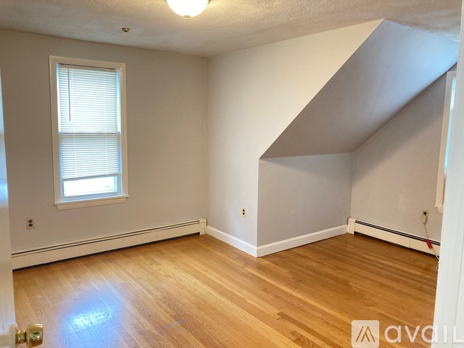 A room with wooden floors and a window with blinds.