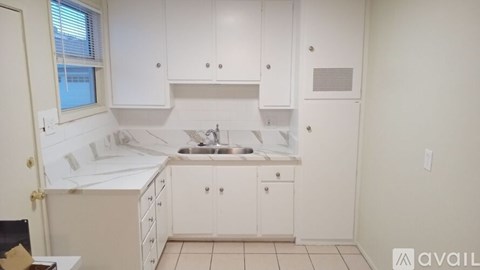 A small kitchen with white cabinets and a sink.