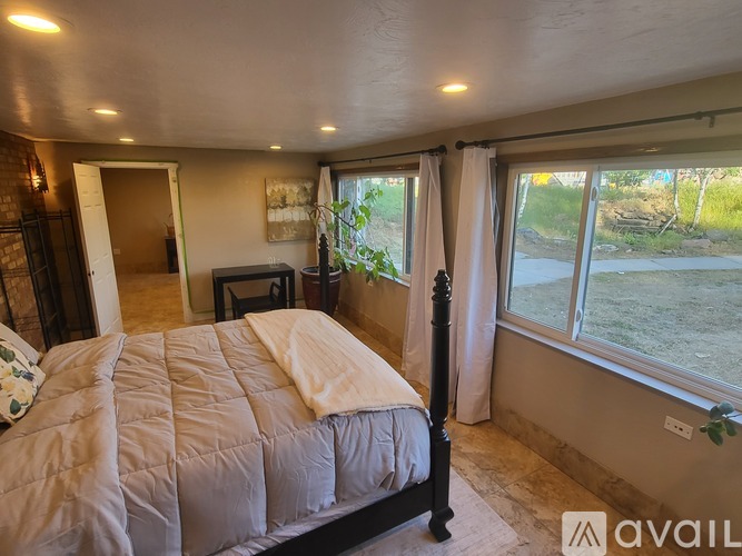 A bedroom with a large bed and a window overlooking a grassy area.
