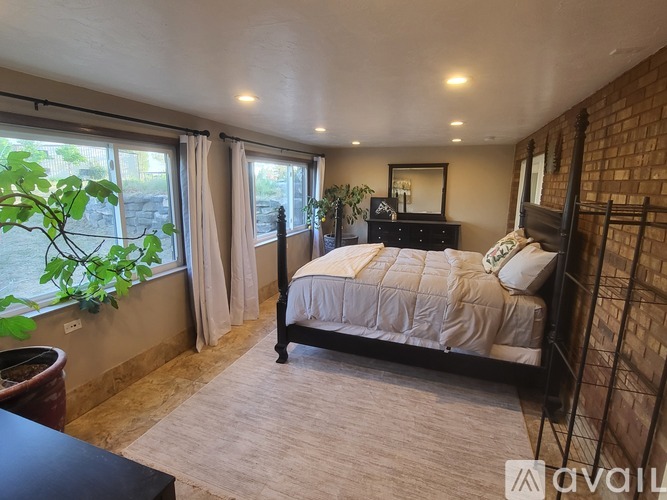 A bedroom with a large bed and a window overlooking a garden.