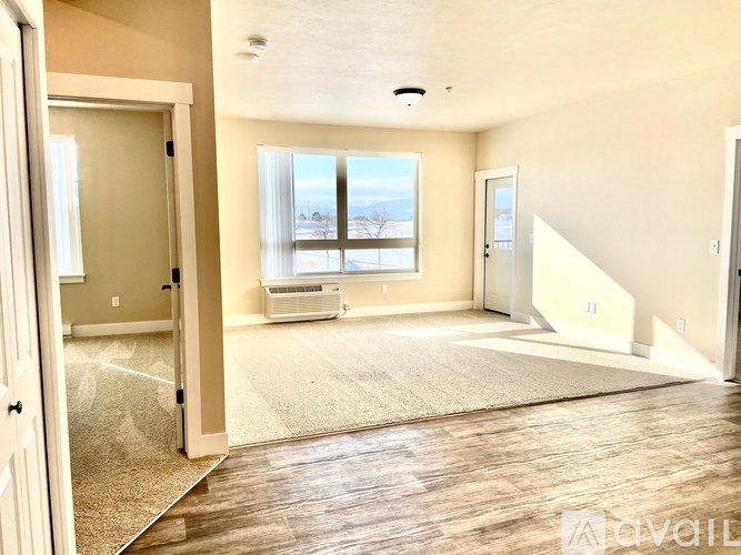 A spacious living room with a large window and a carpeted floor.