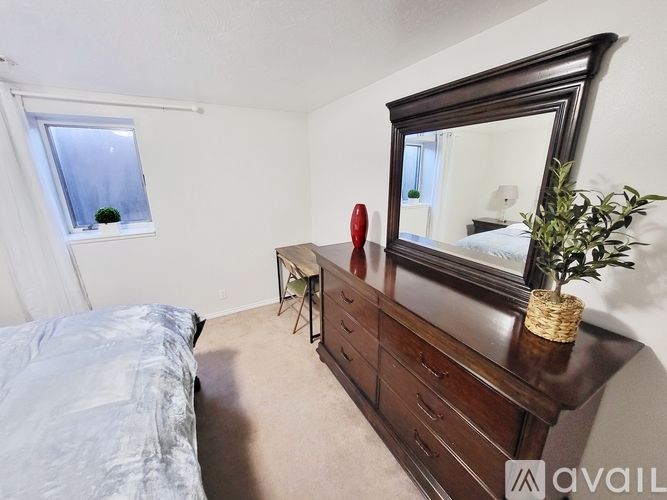 A bedroom with a large bed, a mirror, and a chair.