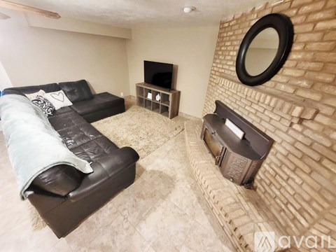 A living room with a black couch and a brick wall.