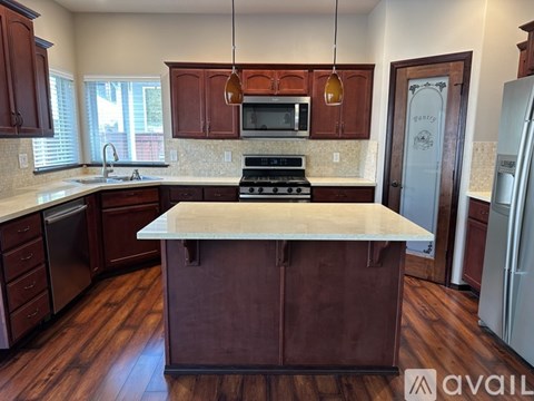 A kitchen with dark wood cabinets and a white island.