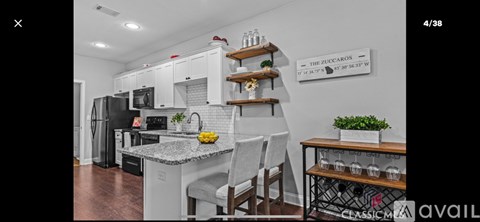 A kitchen with white cabinets and a black refrigerator.