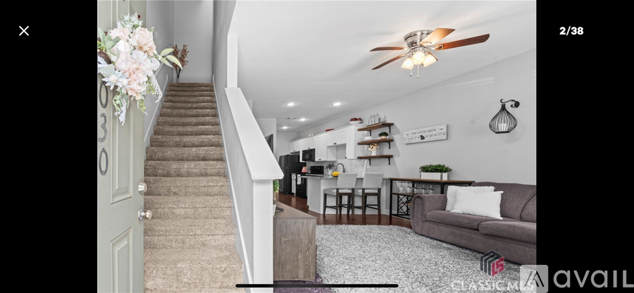 A living room with a staircase and a ceiling fan.