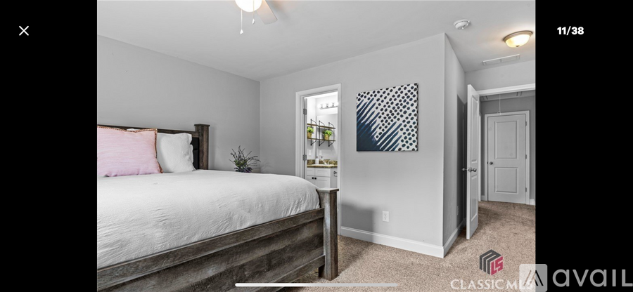 A bedroom with a large bed and a painting on the wall.