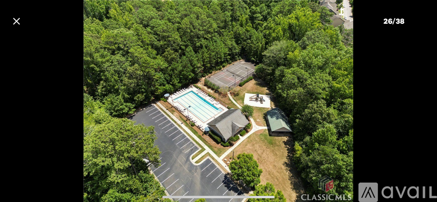 An aerial view of a property with a swimming pool and a parking lot.