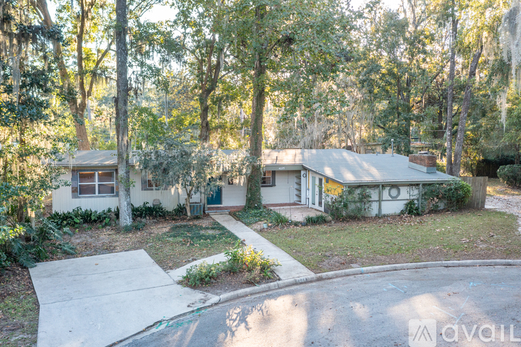 A house surrounded by trees with a driveway in front.