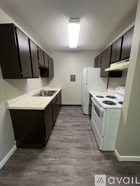 A kitchen with black cabinets and a white fridge.