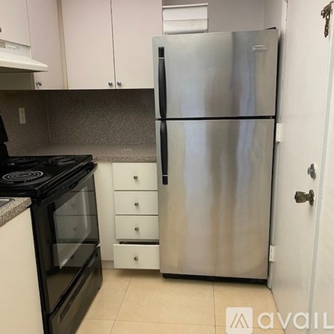 A kitchen with a stainless steel refrigerator and black stove top oven.