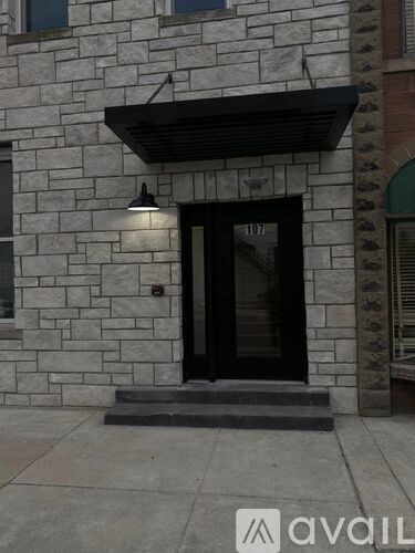 A black door with a glass window is on a stone building.